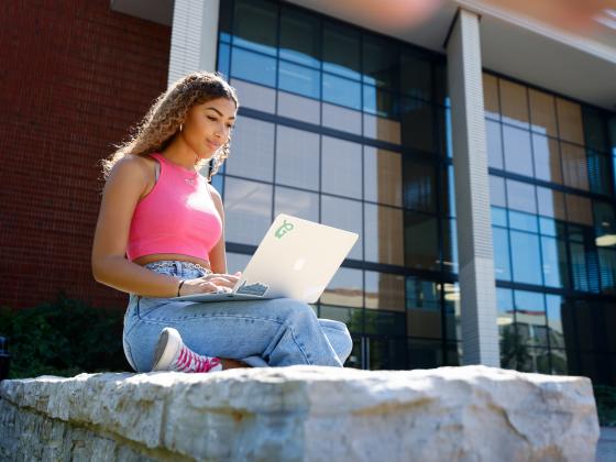 A student works on a laptop outside.